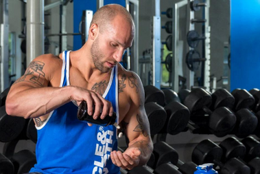 An image of a bodybuilder man taking some supplements